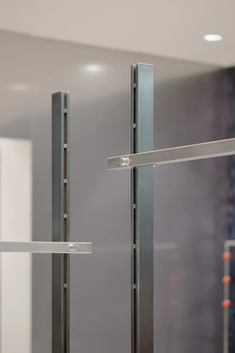Close-up of slotted metal display uprights with adjustable horizontal rail brackets under recessed lighting
