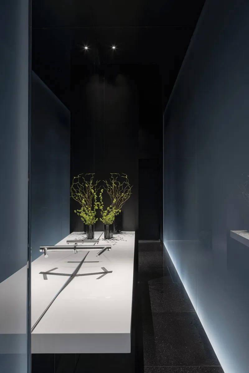 Blue interior passage with illuminated floating display plinth holding two vases with branches