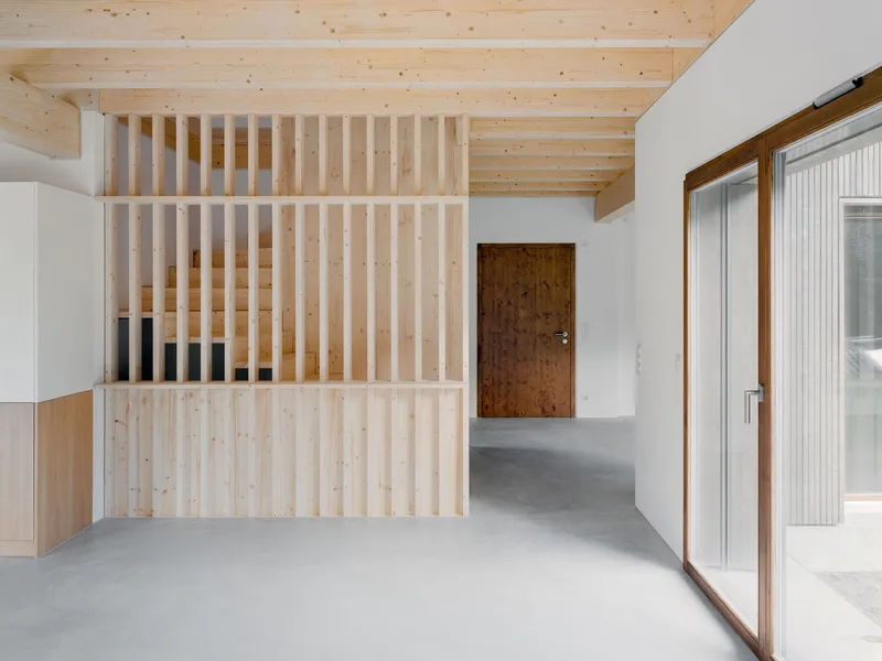 Timber slat screen dividing the entry hall with polished concrete floor under exposed beam ceiling