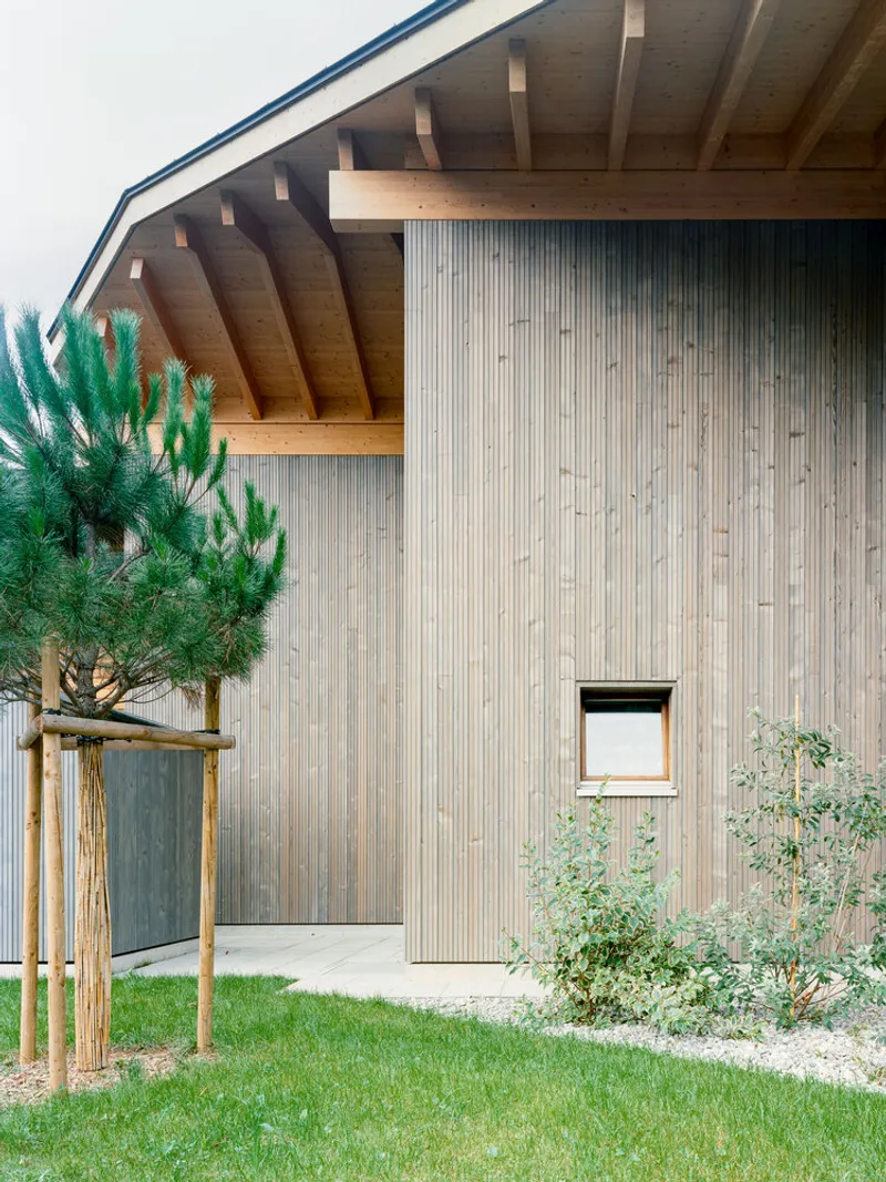 Detail of the overhanging eave with exposed rafters above the vertical wood siding and small window