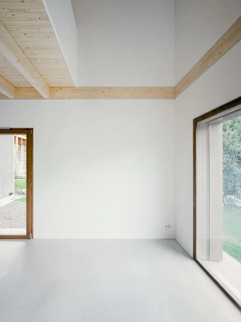 Corner of an interior room with exposed timber ceiling beams and a polished concrete floor