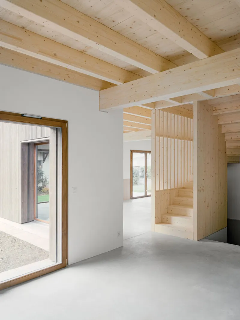 Interior view showing timber staircase and slatted screen divider beneath exposed beam ceiling structure