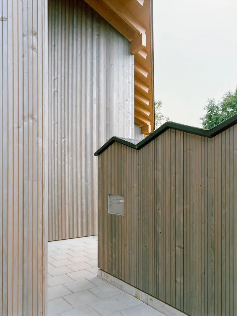 Courtyard passage between corrugated metal cladding and stained timber fence with herringbone paving