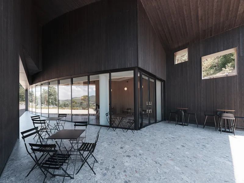Interior courtyard with charred timber cladding and folding glass doors opening to gravel patio