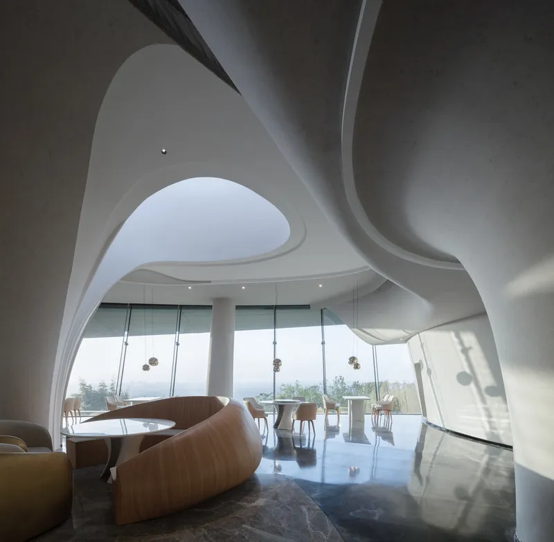 Interior dining space with sculptural white ceiling opening to floor-to-ceiling glazing overlooking distant hills