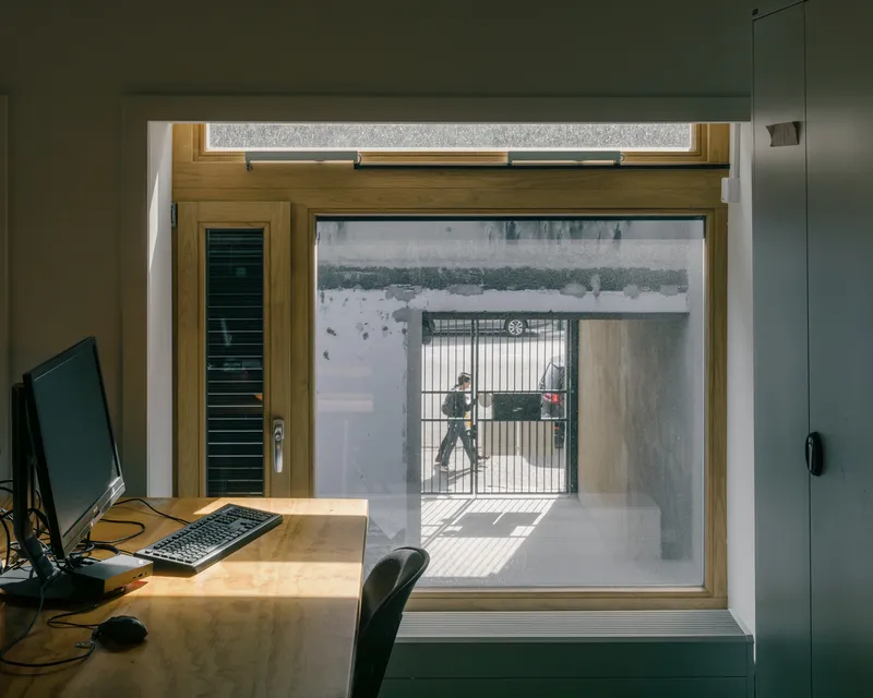 Timber window frame looking through to a courtyard with bicycle and afternoon sunlight casting shadows