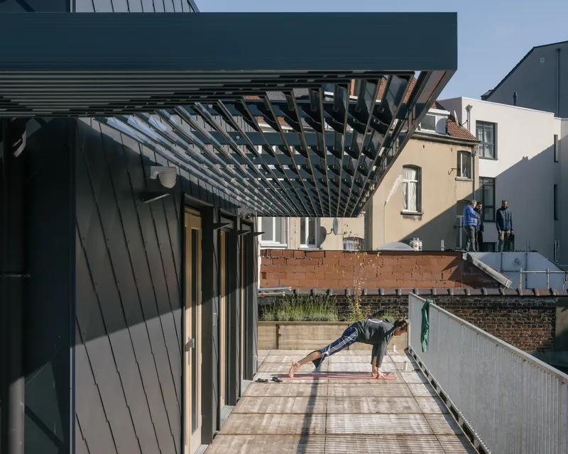 Rooftop terrace with timber slat pergola and person practicing yoga under morning sunlight
