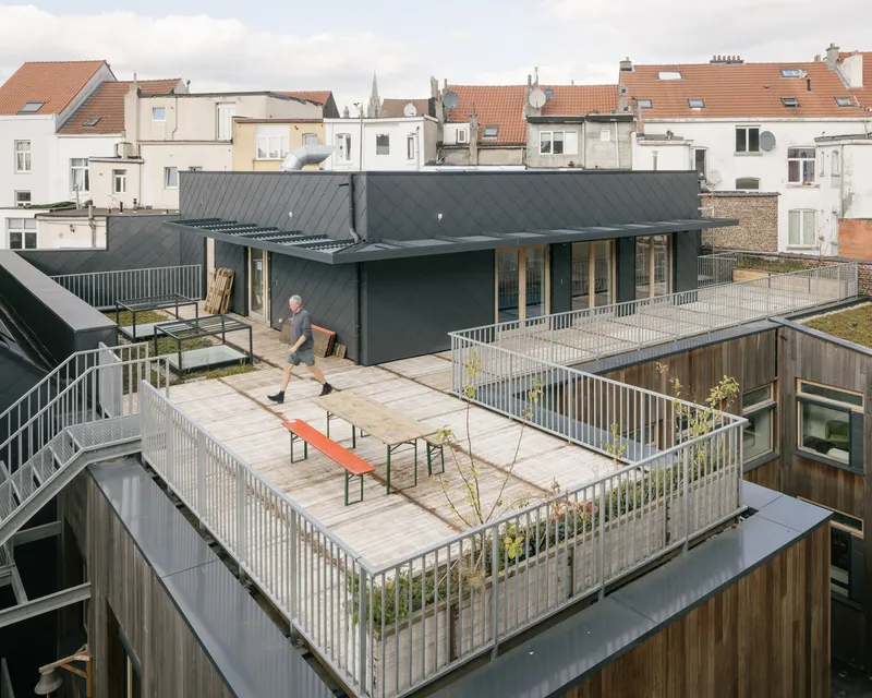 Rooftop terrace with steel railings and timber decking overlooking a dense urban neighborhood with tile roofs