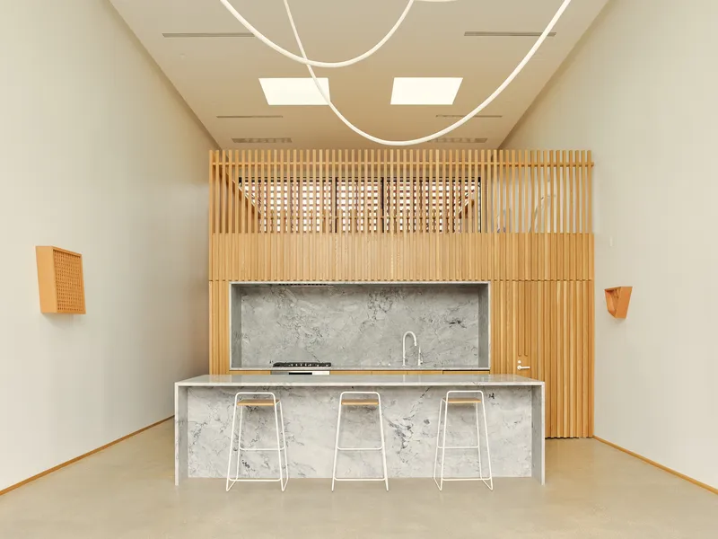 Kitchen island with concrete countertop and three stools beneath circular ceiling light fixture