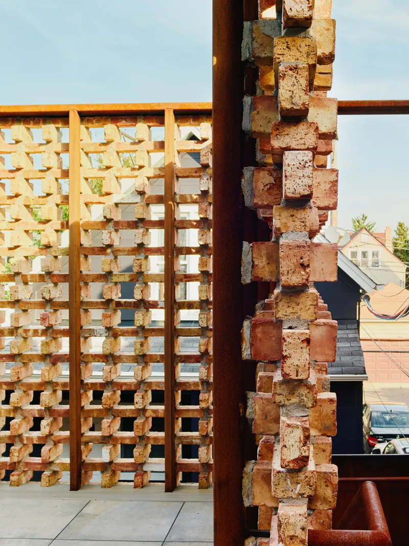 Close-up of stacked brick column meeting timber lattice screen in warm afternoon light
