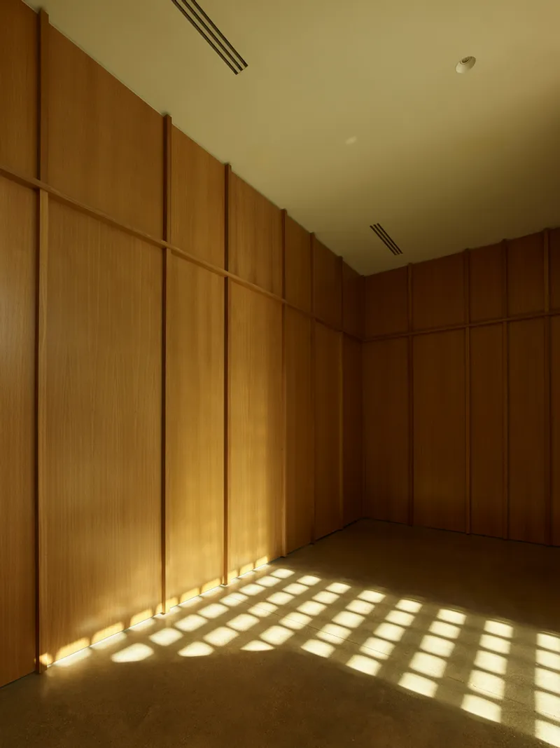Wood-paneled interior room with dappled sunlight patterns cast across floor and walls