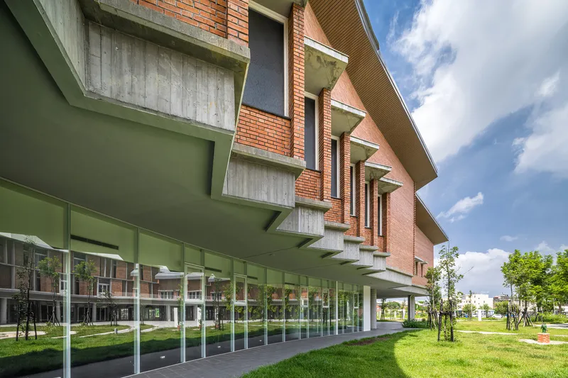 Ground floor colonnade with green painted concrete soffit and paired concrete buttresses above a glazed curtain wall
