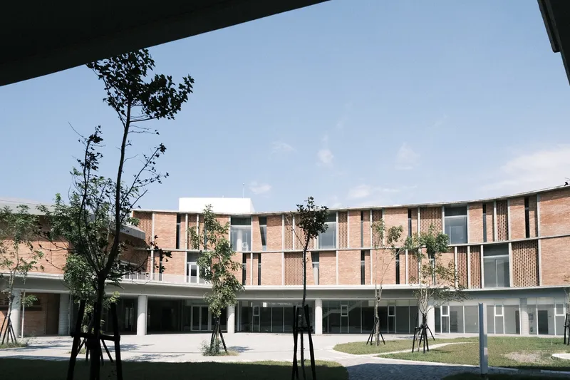 Covered walkway framing view of the central courtyard with brick facades and young trees