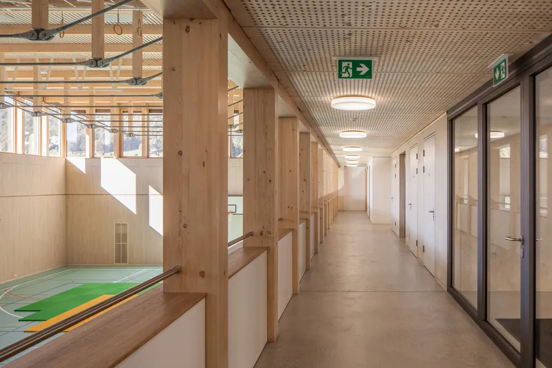 Corridor with perforated timber ceiling overlooking the gymnasium below and glass-fronted rooms along one side