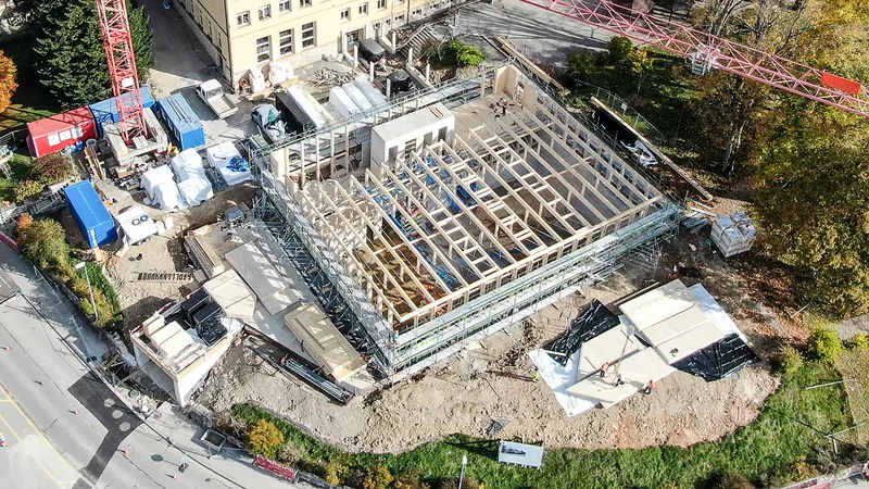 Aerial view of the exposed timber frame structure during construction with crane and material staging areas