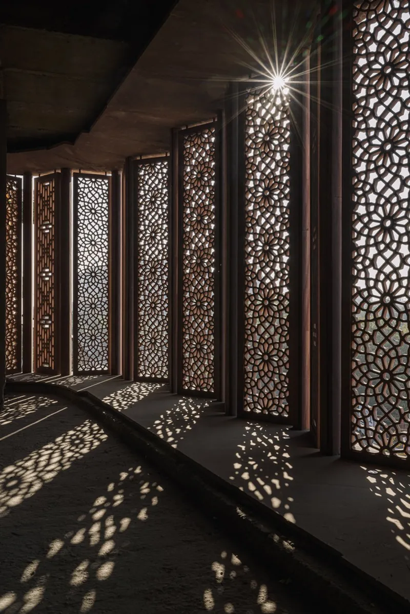 Perforated screen panels casting geometric shadow patterns on dark stone flooring at night