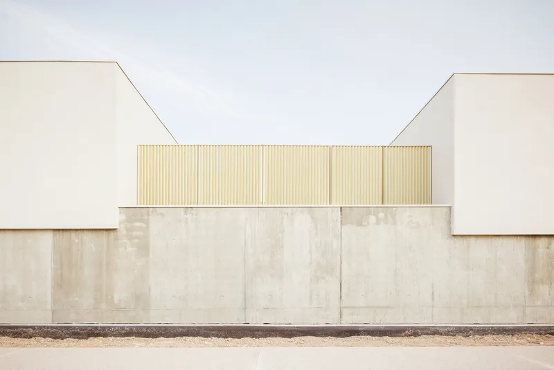 Facade detail showing concrete base wall with vertical timber screen above between white stucco volumes