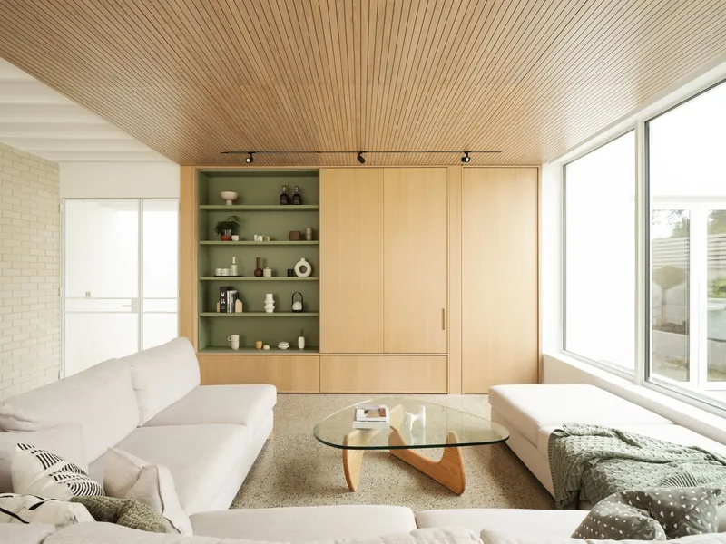 Living room with timber slat ceiling, built-in shelving, and glass coffee table beneath a white pendant lamp