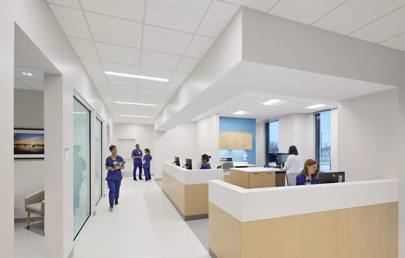White corridor with nurses' station featuring maple millwork and suspended tile ceiling