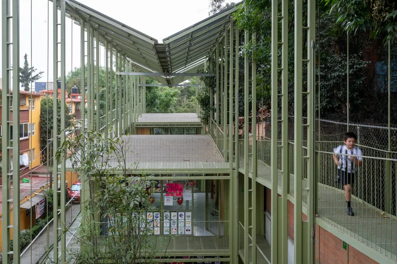 Interior courtyard framed by pale green steel columns and slatted canopy with a child visible on the walkway