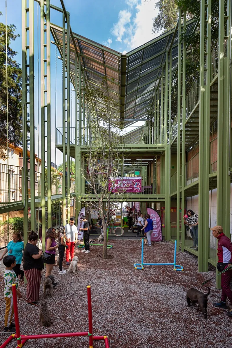 Central courtyard with gravel surface, planted tree, and families gathering beneath the slatted canopy structure