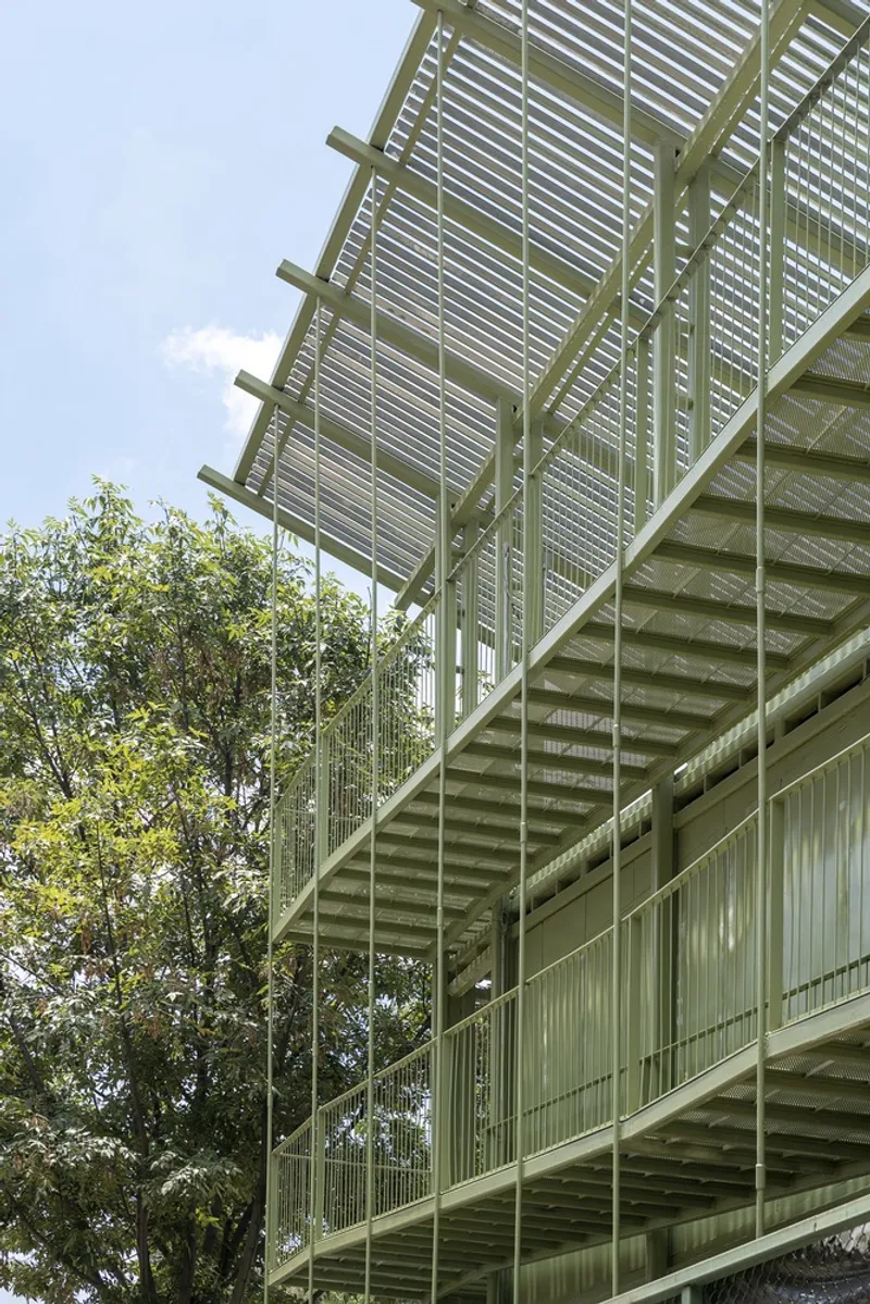 Exterior elevation showing cantilevered walkways with slatted screens and horizontal louvered canopy against blue sky