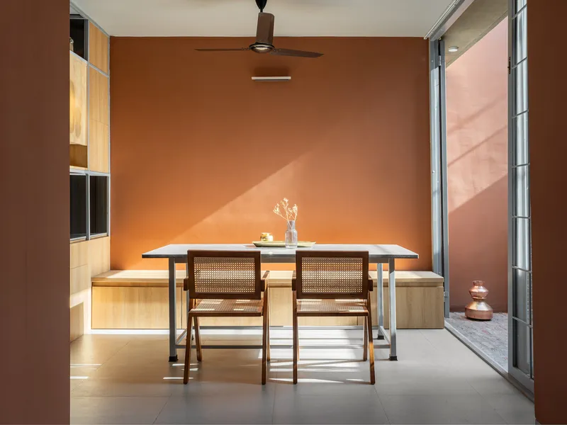 Dining area with cane-backed chairs and timber cabinetry opening onto a terracotta-paved courtyard