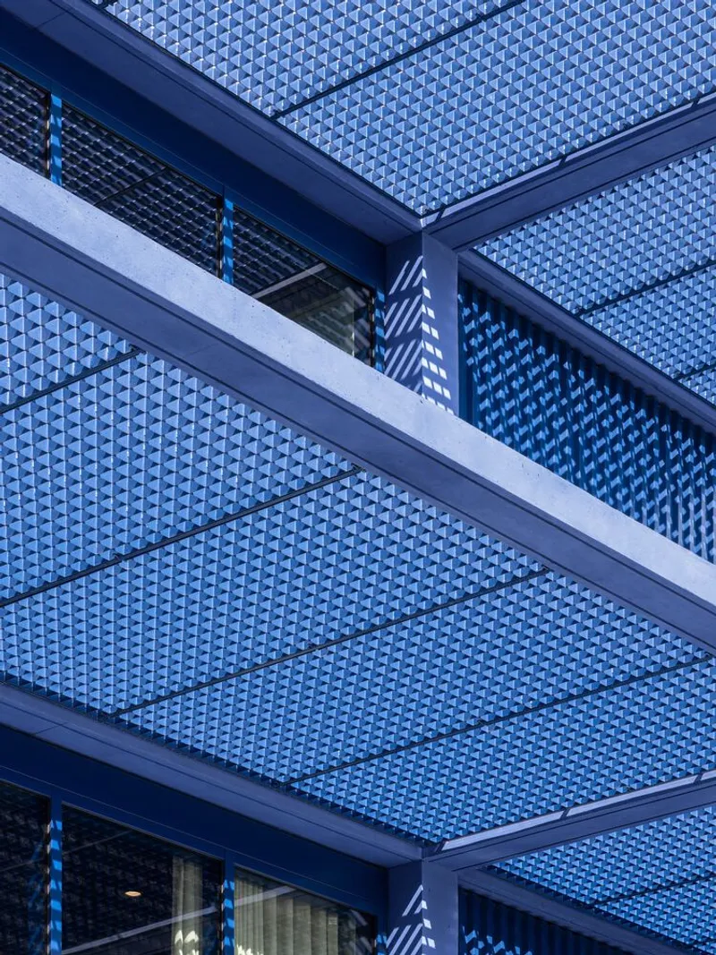 Facade detail showing textured blue panels and steel beams framing the building layers