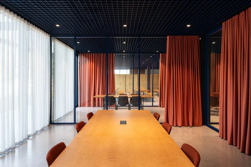 Meeting room with timber table and orange fabric dividers beneath a dark slatted ceiling