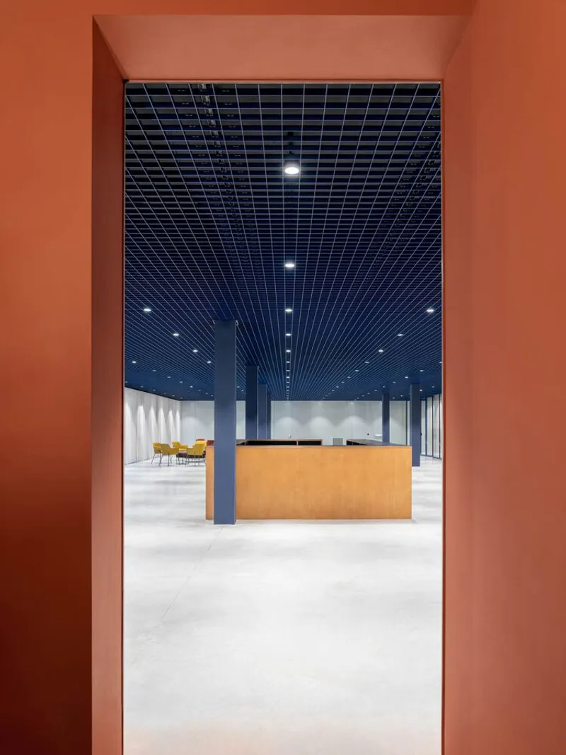 View through an orange-painted doorway into a reception area with timber desk and grid ceiling