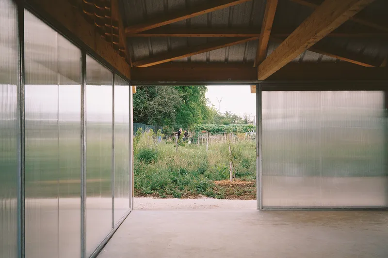 Interior view through open translucent panels toward a garden with visitors in the distance