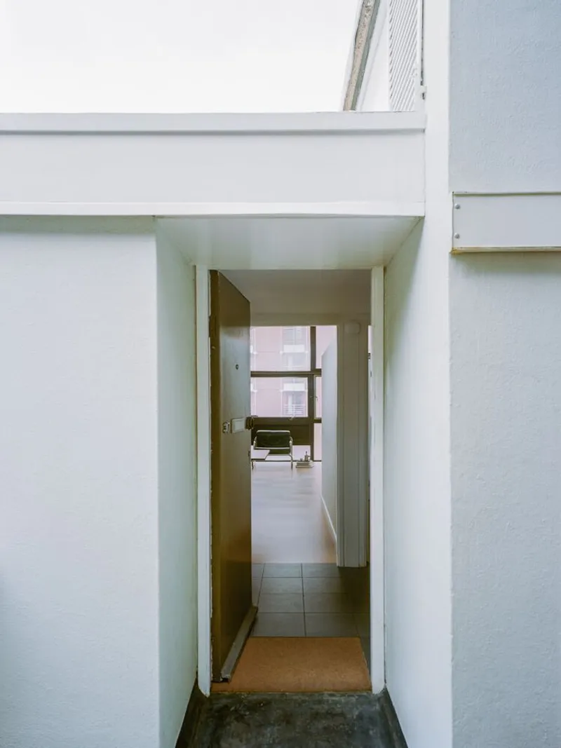 Narrow entrance corridor with white walls leading to an interior room beyond
