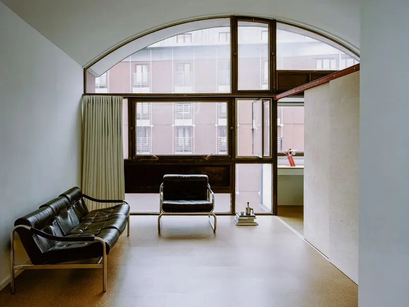 Living room with arched dark timber window framing a view of the adjacent residential building
