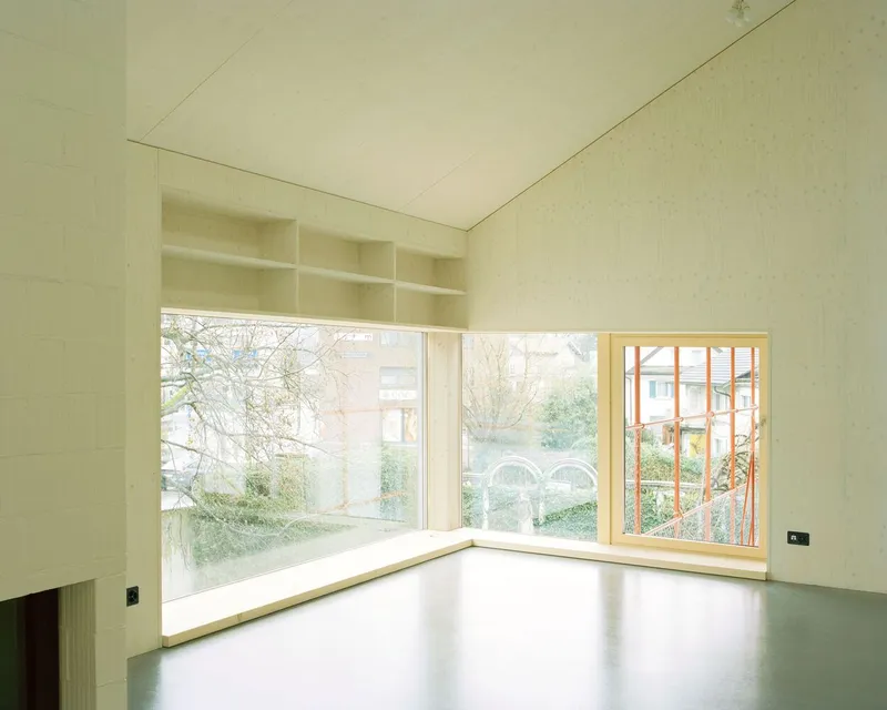 Corner window seat with built-in shelving above and views of neighboring gardens in soft daylight