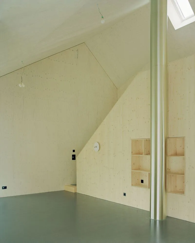 Interior room with pale wood wall integrating a recessed niche and skylight above