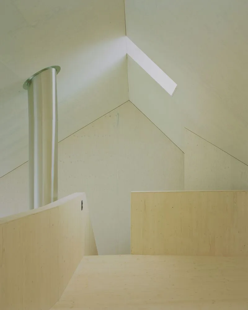 Pale plywood staircase with skylight above and white fabric curtain hanging at the landing