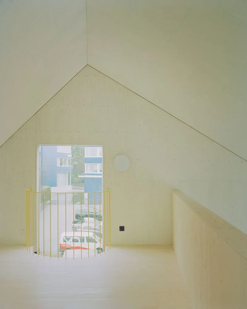 Upper floor room with yellow metal railing at the glazed door overlooking neighboring buildings