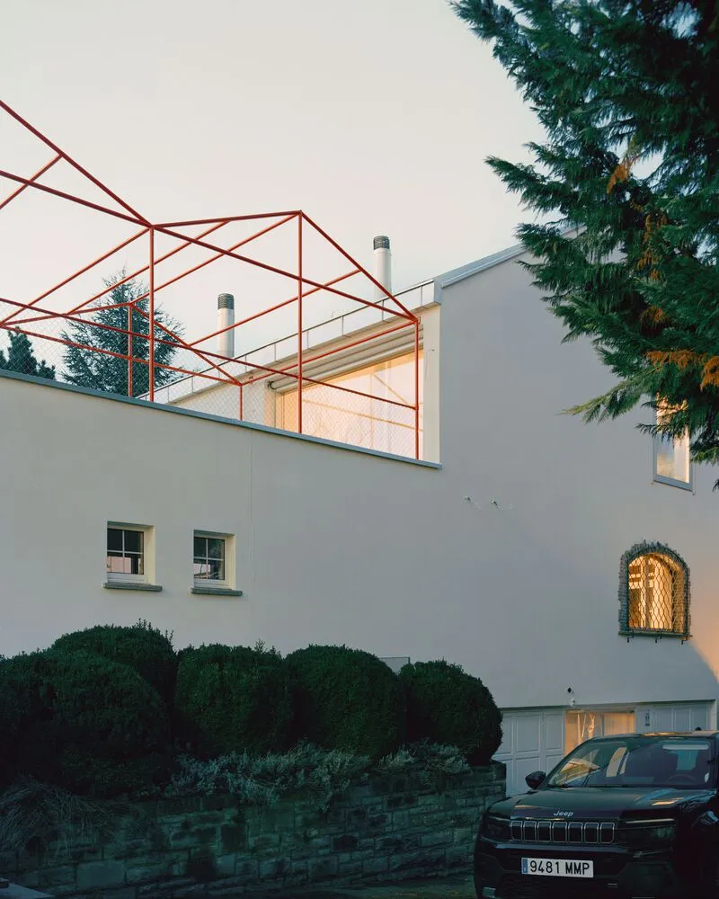 Rooftop terrace with red steel pergola frame and mesh balustrade at dusk
