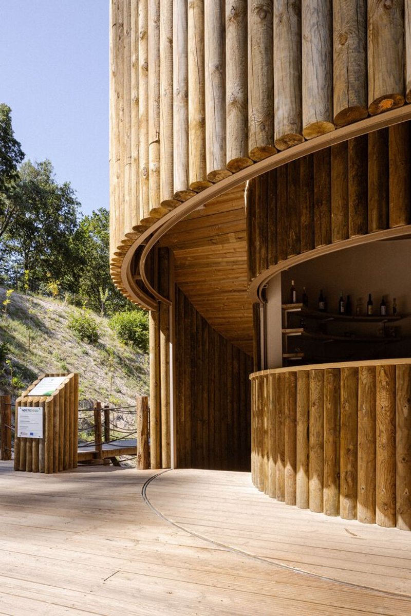 Close-up of curving timber counter and vertical log cladding under a ribbed wooden soffit