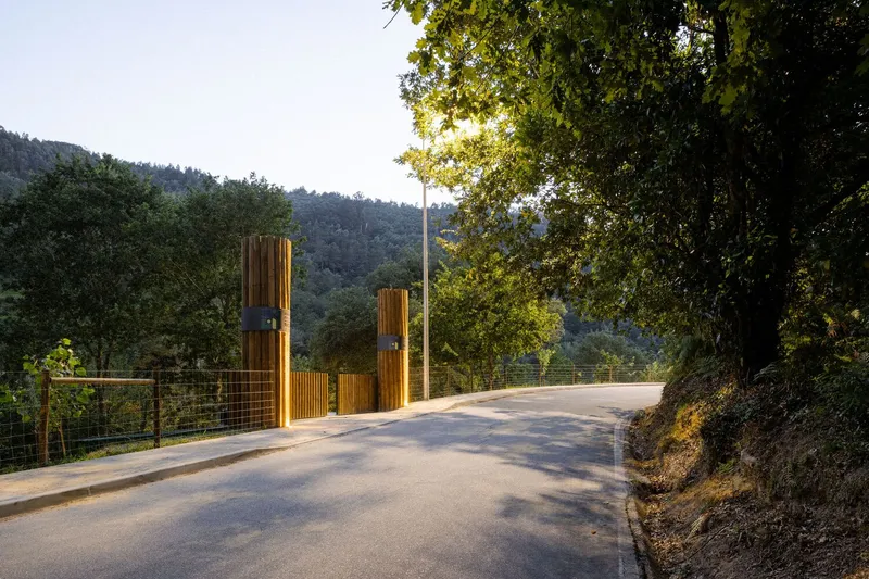 Entry road with timber posts and wire mesh railing approaching the compound at dusk