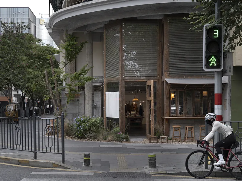Street view of the curved concrete facade with timber-framed glazing and a cyclist passing by