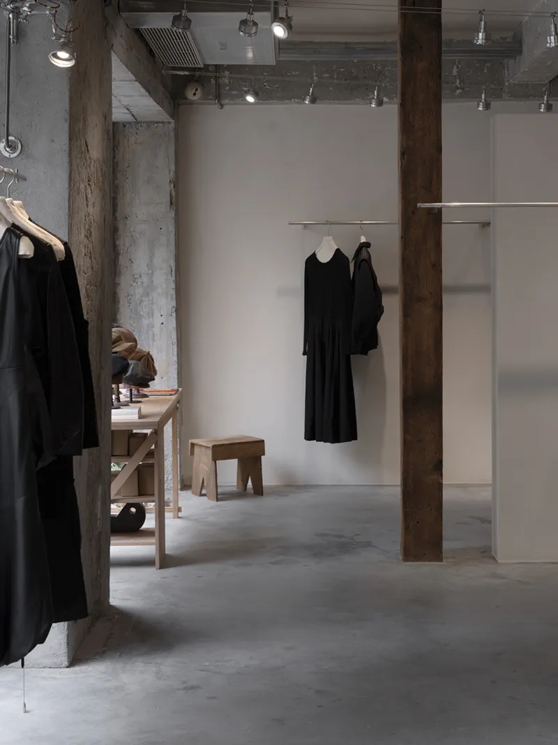 Retail display area showing exposed timber columns against white partitions with concrete floor and track lighting