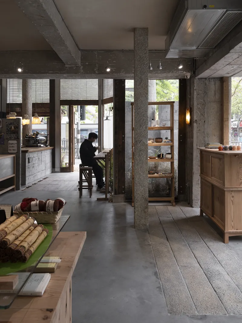 View through exposed concrete columns toward a seated figure silhouetted against the street-facing windows