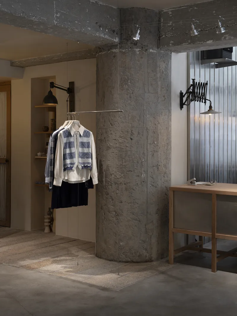 Exposed concrete column and beam with track lighting above a minimalist retail display area