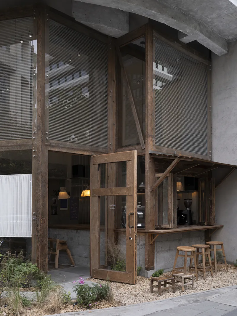 Timber framed entrance with glazed door and upper level blinds beneath concrete slab