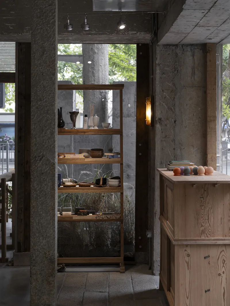 Interior view of timber shelving unit between concrete columns with street view beyond