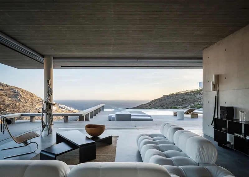 Living room with ribbed timber ceiling and retractable glass walls opening to the terrace and sea