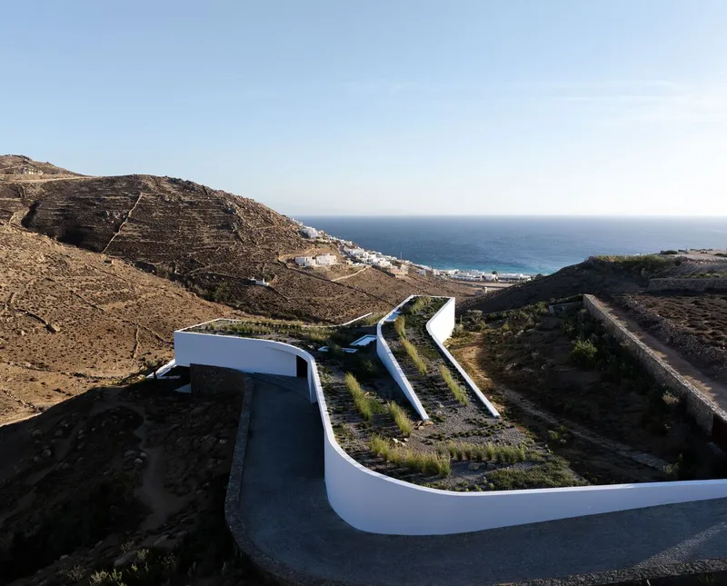 Aerial view of the curving white retaining walls and planted courtyard descending toward the coastline