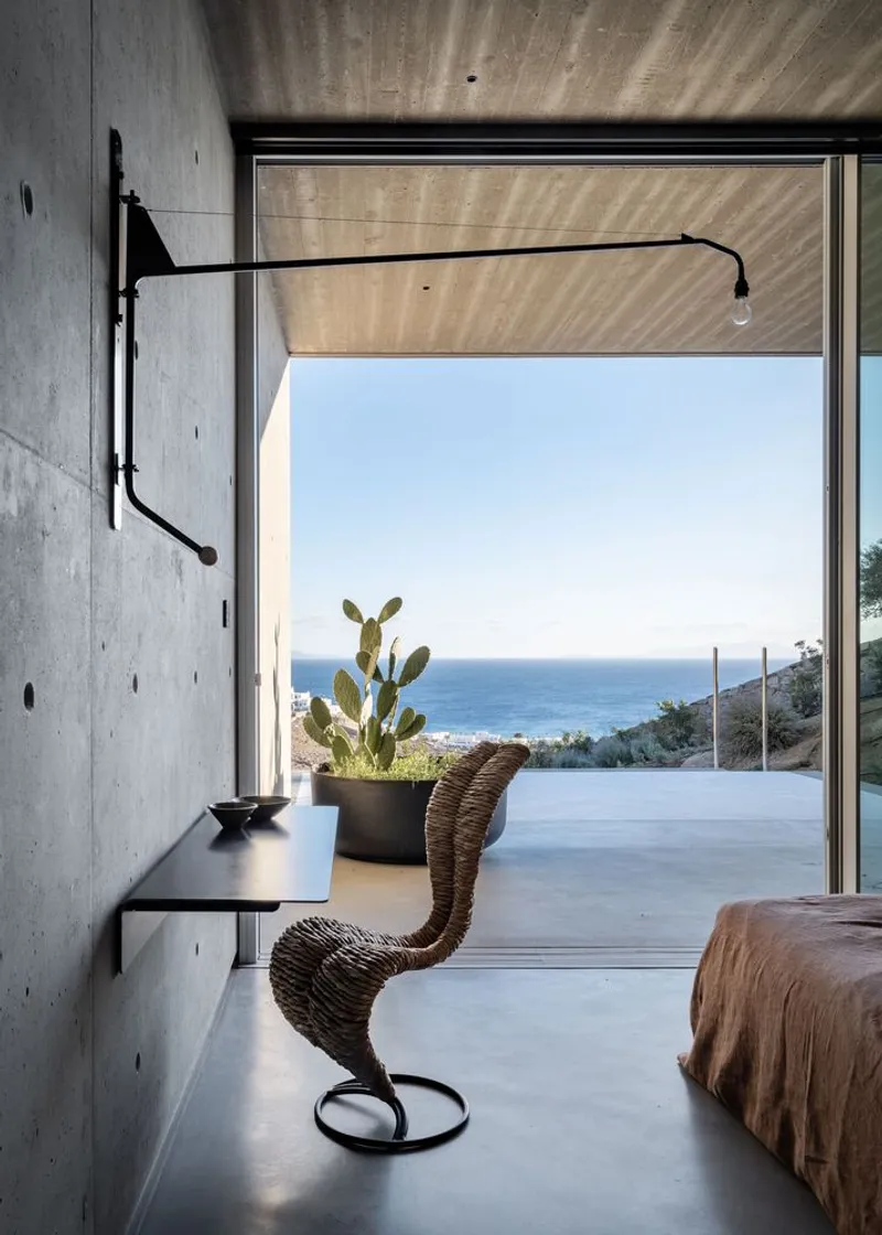 Interior view through full-height glazing to infinity pool terrace and ocean beyond