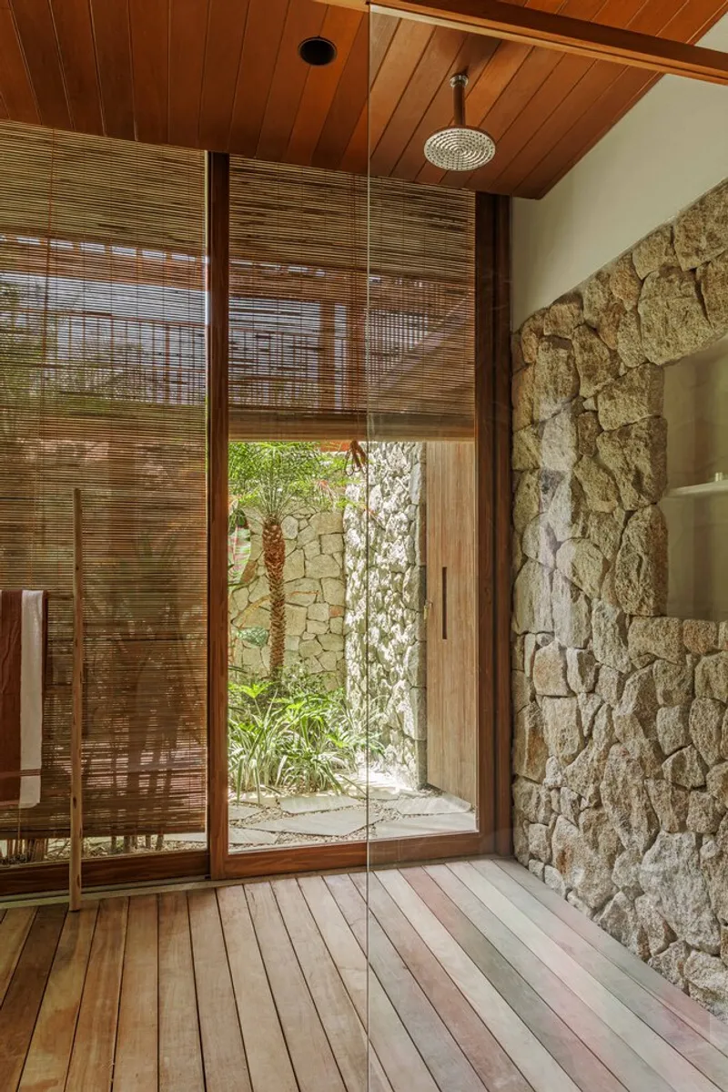 Timber-framed shower enclosure with bamboo screens and rough stone wall beneath wood-paneled ceiling